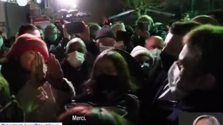 Face à Emmanuel Macron, une femme tend ses mains sur lesquelles on peut-y lire le message « Je t’emmerde »